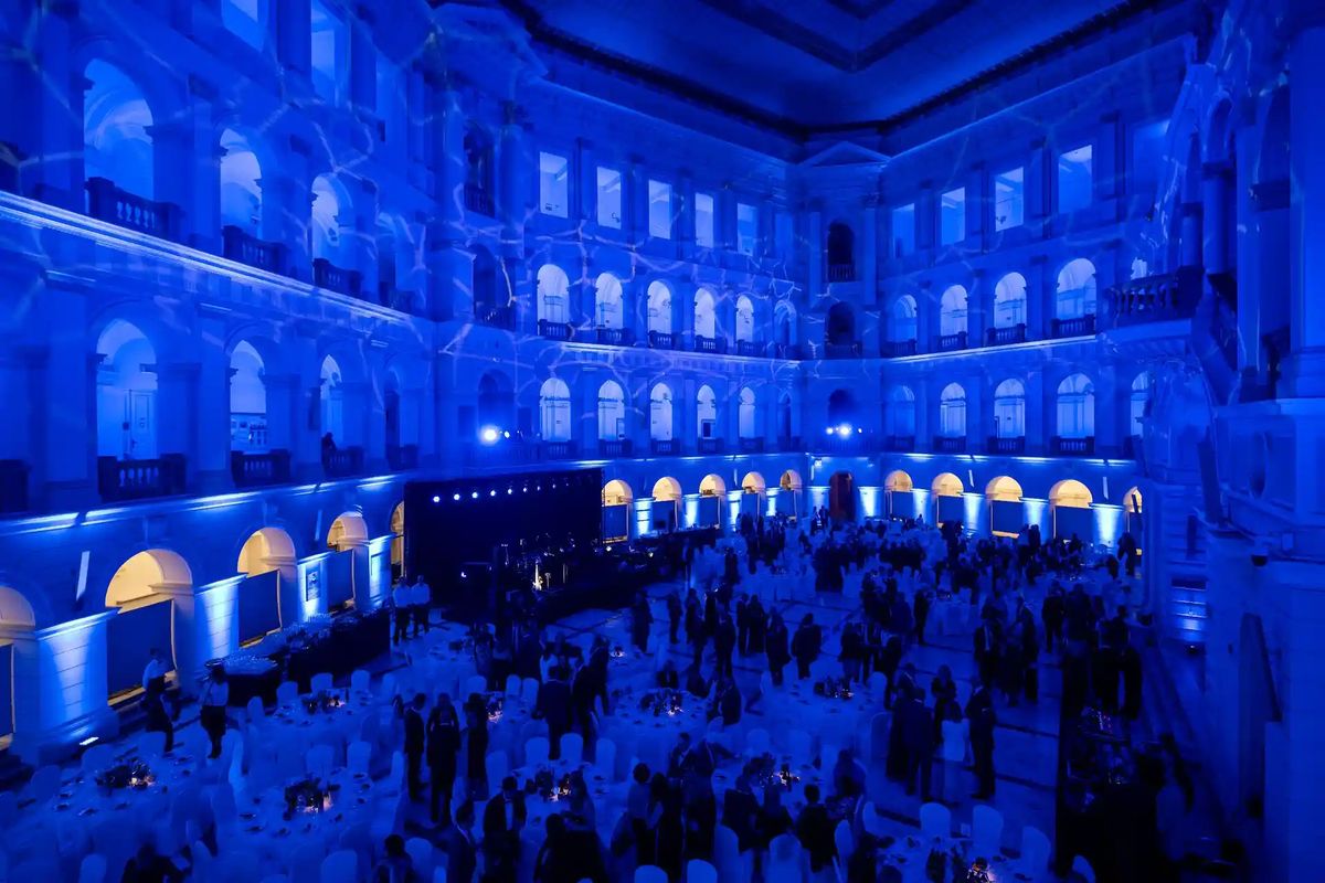 Gala dinner in a grand arched hall with round tables and stage lighting